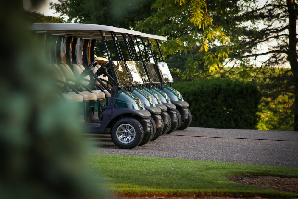  Five empty golf carts are parked on the road. 