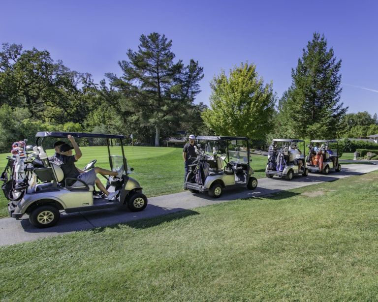 people are sitting in four golf carts at a course.